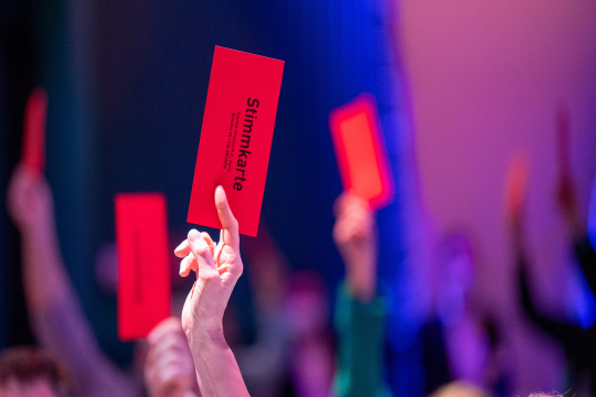 Hand, die eine rote Stimmkarte hochhält