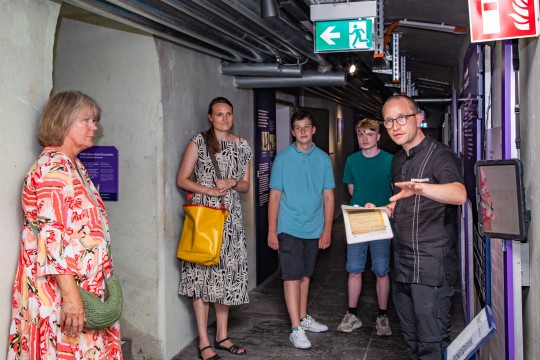 Foto: Menschengruppe wird durch die Gedenkstätte geführt