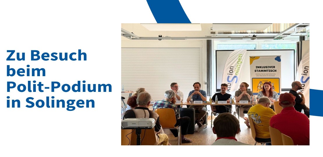 Auf dem Bild sind Menschen zu sehen. Sie sitzen vor einem Publikum.