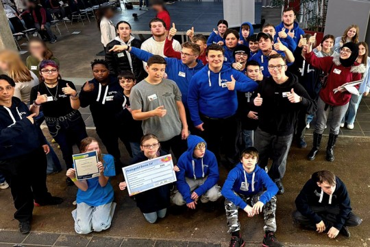 Eine Gruppe von Schüler*innen, die in die Kamera schauen. Viele halten den Daumen hoch.