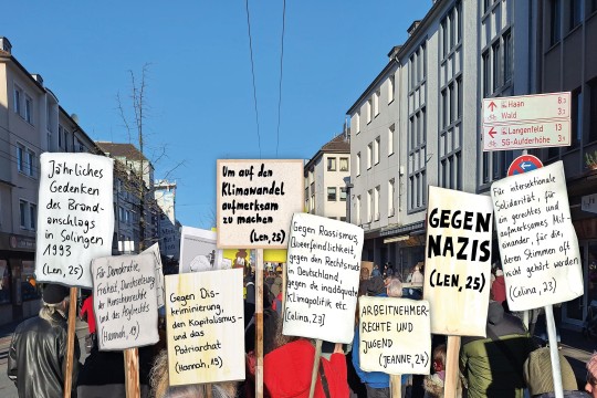 Foto: hochgehaltene Schilder während einer Demonstration mit Aufschriften wie 